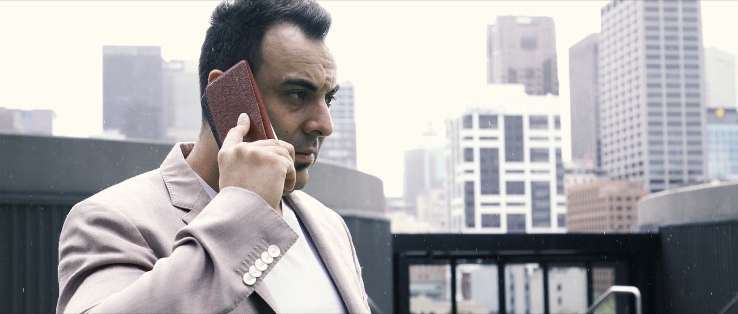 Sam Bashiry on the phone with Melbourne city buildings behind him