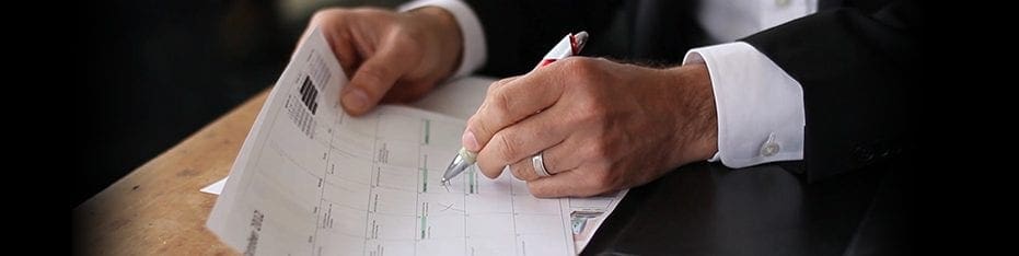 A person writing in a paper calendar with a pen.