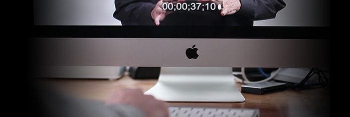 An archive photograph of an iMac displaying a video frame with an on-screen timecode.