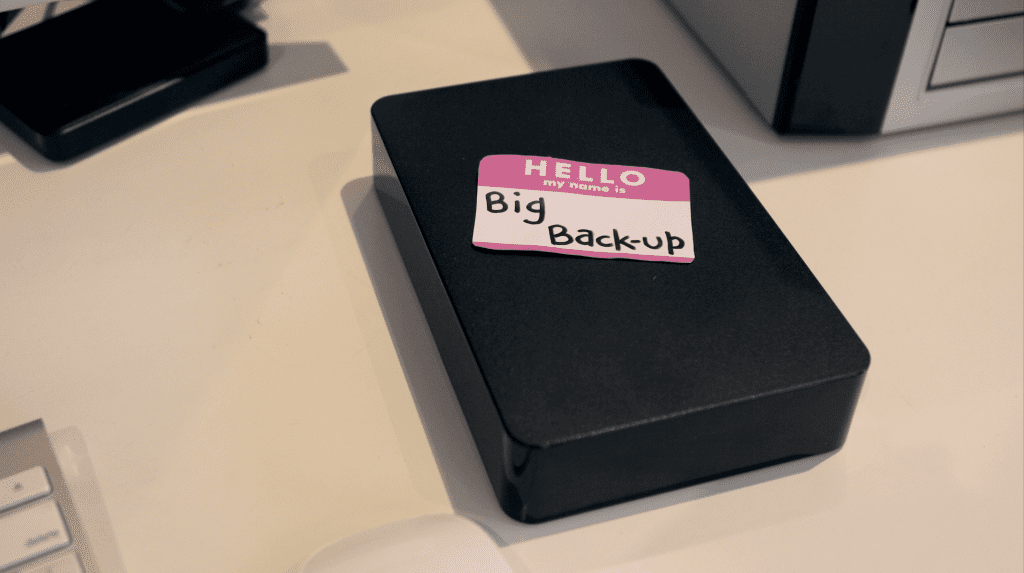 A black external storage device on a desk with a handwritten Big Back-up label.