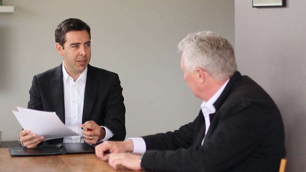 Two people seated at a table discussing printed pages.