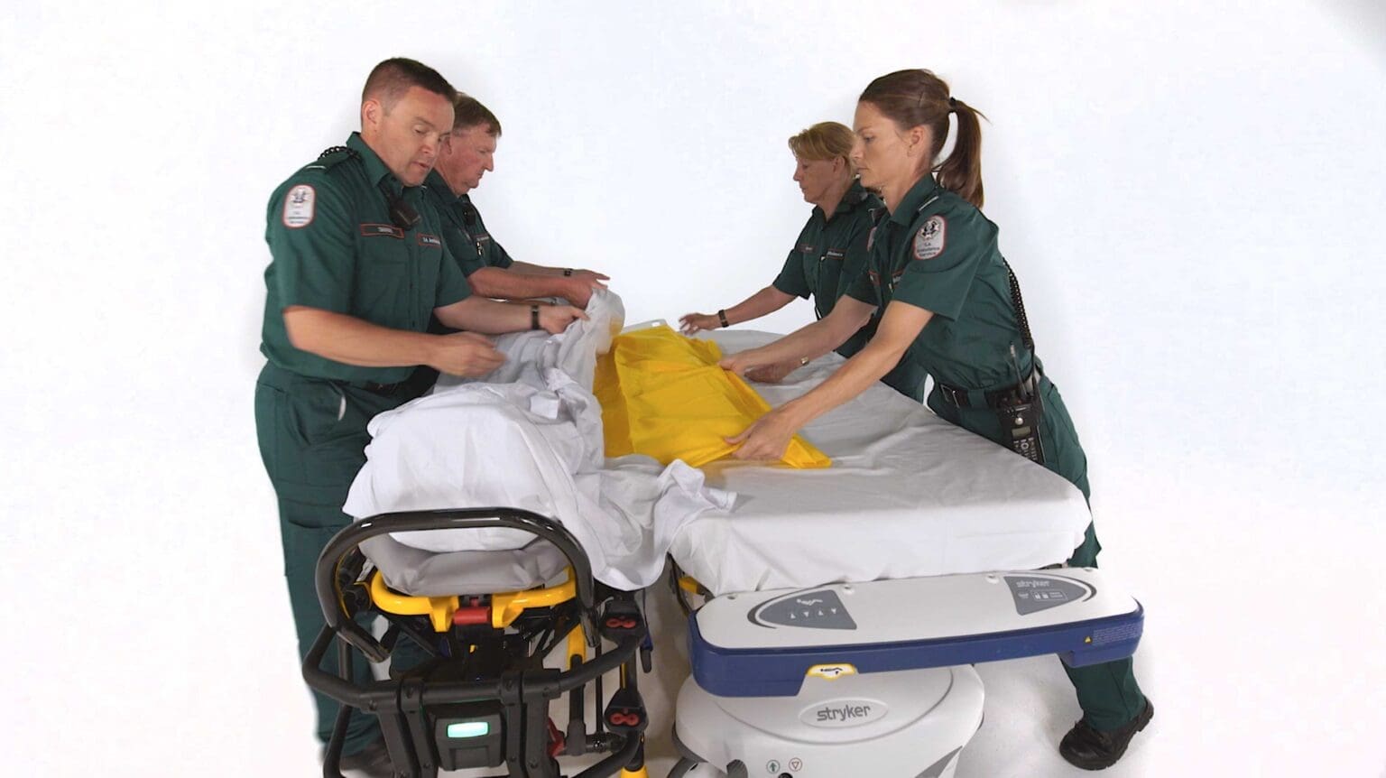 Ambulance personnel demonstrating a patient transfer using Stryker equipment in the studio