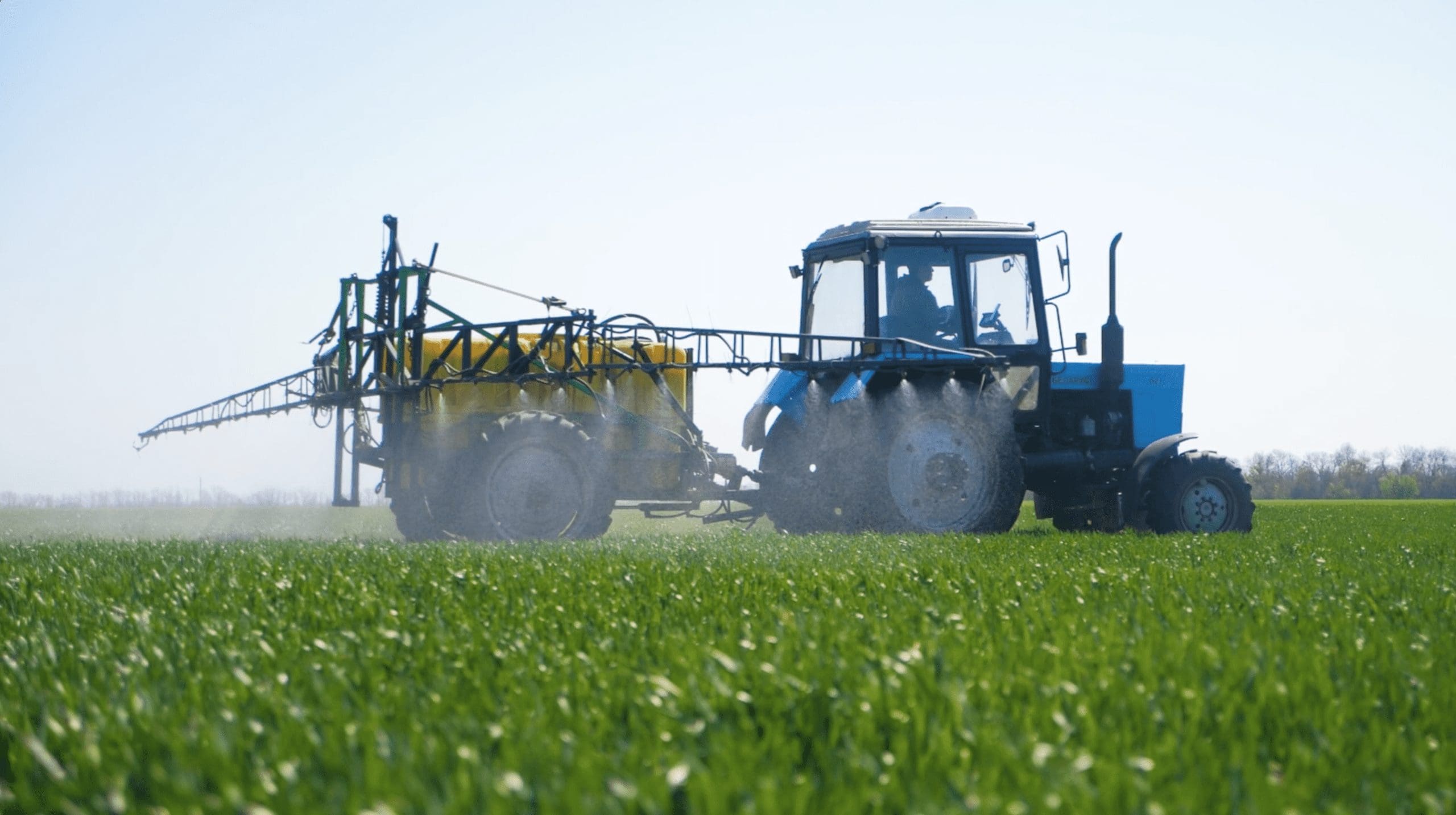 Ground-level farming footage of a tractor working across a crop field