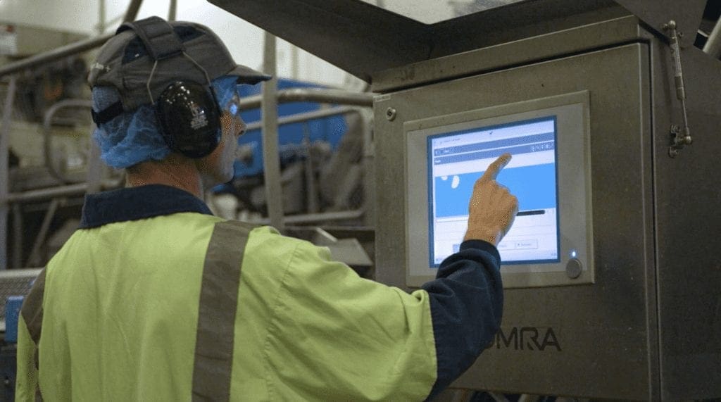 A person wearing hearing protection operating an industrial touchscreen.