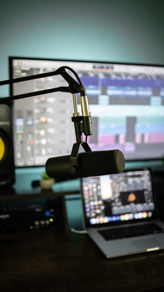 A microphone on an adjustable arm in front of recording screens.