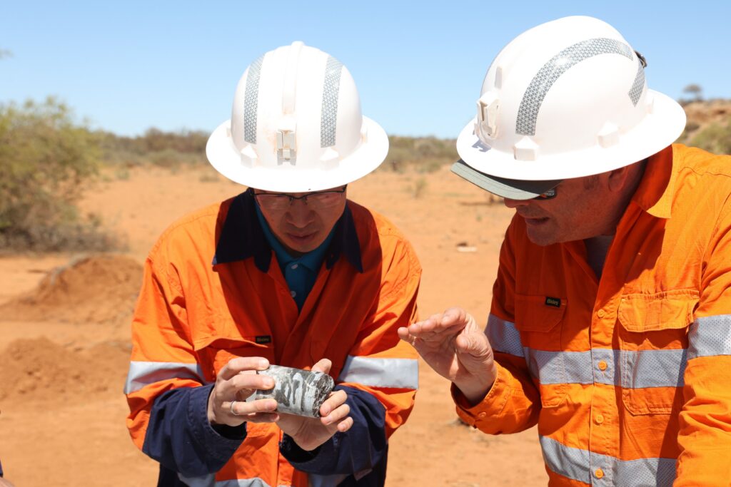 2 men on mine site inspecting metal object