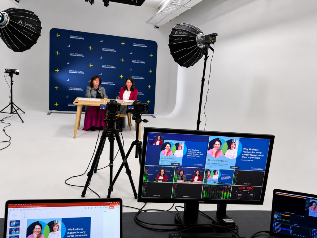 two people sitting at a desk talking to the camera