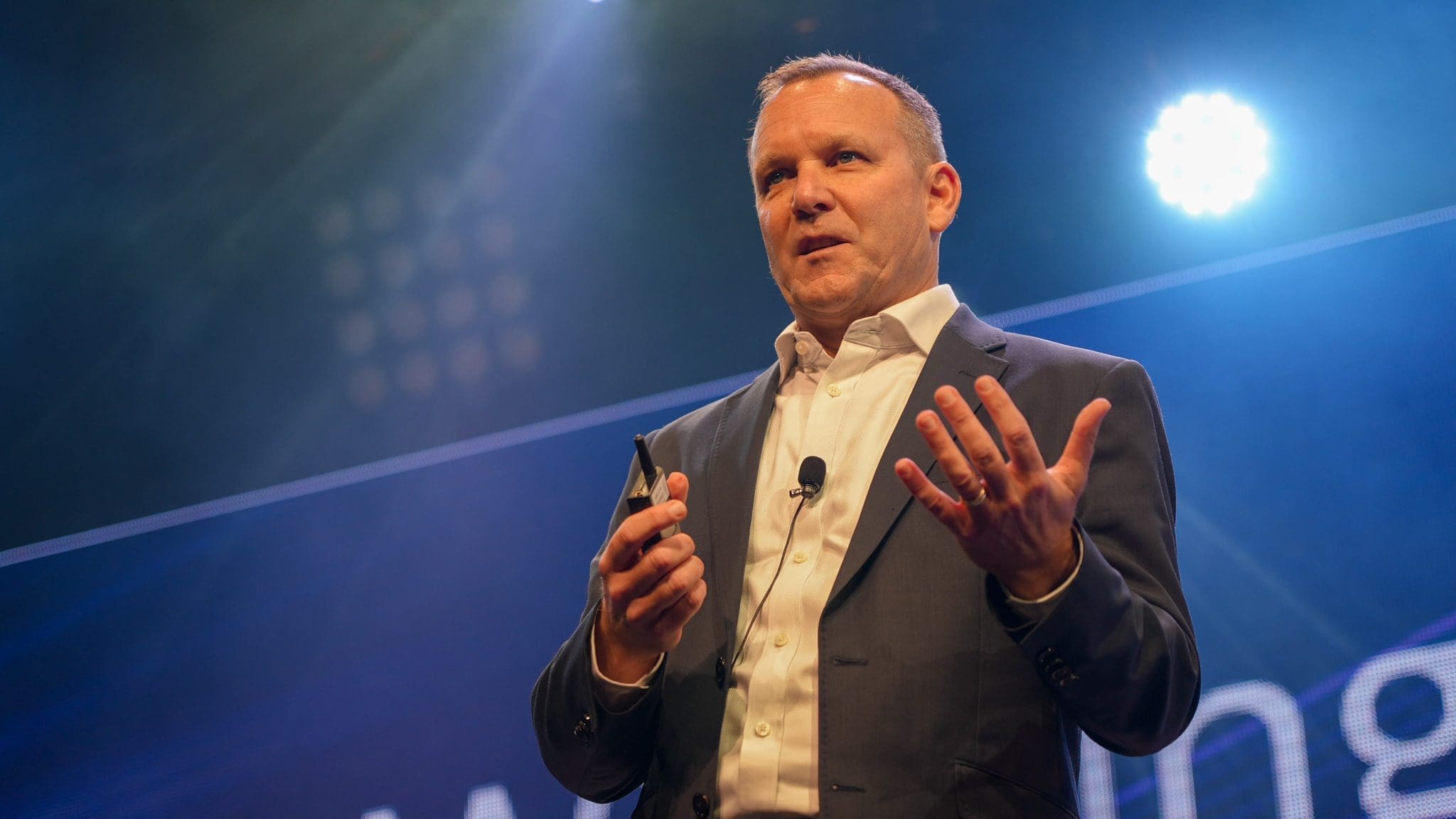 Corporate speaker presenting on stage under event lighting