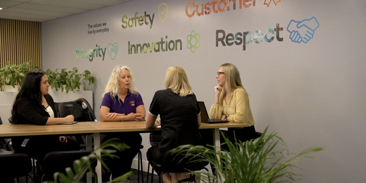 Four women talking around a table in a workplace scene