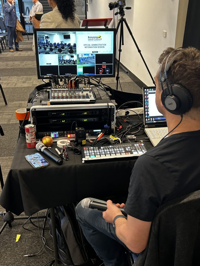 Live streaming technician managing multi-camera production, audio, presentation switching and recording during a Bunurong Land Council hybrid meeting.