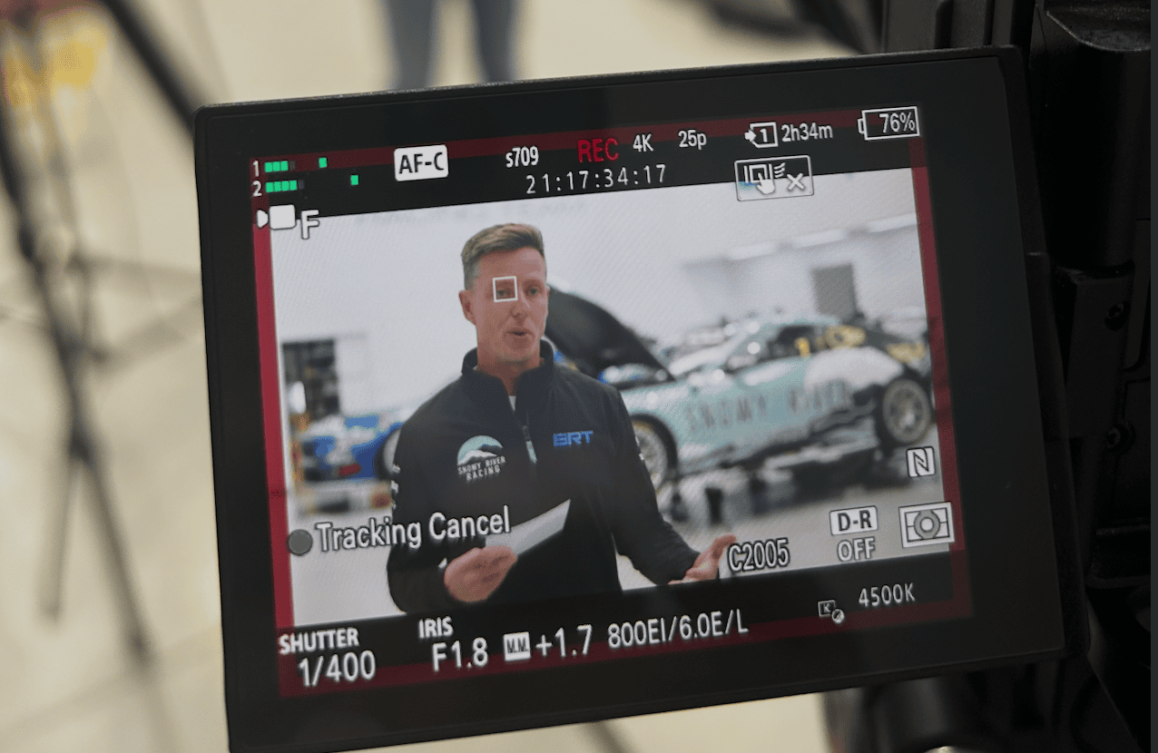 Camera monitor showing a presenter and video exposure information