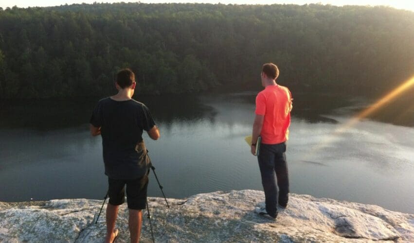 Two people filming above a lake at sunset during Dream Engine's USA production trip